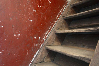 老损坏的棕色（的）木楼梯和红色的墙领先的的阁楼需要改造特写镜头老损坏的棕色（的）木楼梯和红色的墙领先的的阁楼需要改造