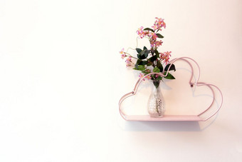 装饰粉红色的架子上白色墙与玻璃花瓶和粉红色的明亮的花现代浪漫的装饰室内背景装饰粉红色的架子上白色墙与玻璃花瓶和粉红色的明亮的花现代浪漫的装饰室内