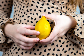 年轻的美丽的女人持有新鲜的黄色的柠檬她的手特写镜头夏天水果概念健康的年轻的美丽的女人持有新鲜的黄色的柠檬她的手特写镜头夏天水果概念