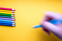 彩色的铅笔行彩虹颜色手与蓝色的彩色的铅笔吸引了橙色纸复古的背景空间为文本彩色的铅笔行彩虹颜色手与蓝色的彩色的铅笔吸引了橙色纸复古的背景