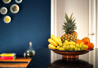 新鲜的水果碗现代室内附近黑暗蓝色的墙的厨房美丽的现代设计首页菠萝香蕉和各种各样的水果复古的房子特写镜头新鲜的水果碗现代室内附近黑暗蓝色的墙的厨房美丽的现代设计首页菠萝香蕉和各种各样的水果复古的房子