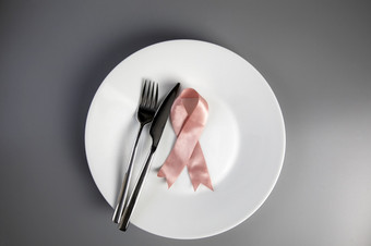 粉红色的丝带白色板与刀和叉乳房癌症意识概念前视图医疗健康和食物概念复制空间粉红色的丝带白色板与刀和叉乳房癌症意识概念前视图医疗健康和食物概念