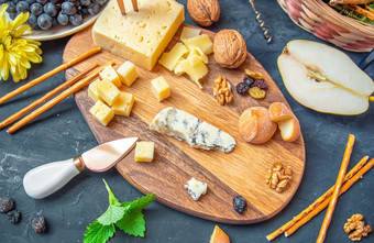 奶酪板从不同的种类奶酪爱蒙塔尔自制的帕尔玛蓝色的奶酪面包棒核桃葡萄干梨葡萄黑色的表格奶酪板从不同的种类奶酪爱蒙塔尔自制的帕尔玛蓝色的奶酪面包棒核桃葡萄干梨葡萄表格