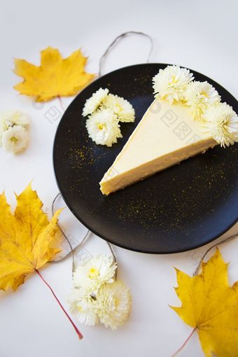 奶油芝士蛋糕背景黄色的秋天叶子和花特写镜头奶油芝士蛋糕背景黄色的秋天叶子和花特写镜头