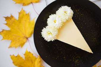 奶油芝士蛋糕背景黄色的秋天叶子和花特写镜头奶油芝士蛋糕背景黄色的秋天叶子和花特写镜头