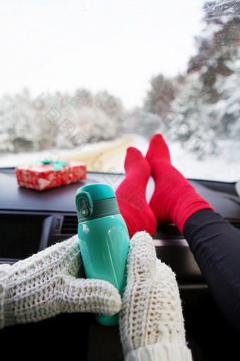 的女孩持有热水瓶而坐着的车冬天的背景的冬天森林旅行旅行和冬天概念的女孩持有热水瓶而坐着的车冬天的背景的冬天森林旅行旅行和冬天概念