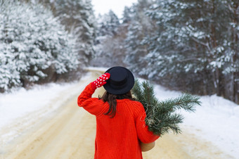 女孩红色的毛衣和他红色的连指手套站的中间白雪覆盖的路森林与松分支机构周末旅行女孩红色的毛衣和他红色的连指手套站的中间白雪覆盖的路森林与松分支机构周末旅行