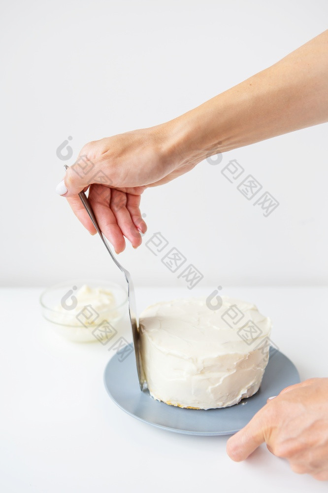 美味的奶油蛋糕那的女孩传播在的生奶油与抹刀的蛋糕准备好了为装饰美味的奶油蛋糕那的女孩传播在的生奶油与抹刀的蛋糕准备好了为装饰