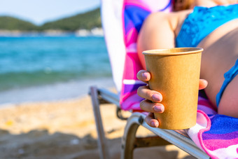 关闭女女孩女人手持有冰 沙冰咖啡的海滩而放松日光浴浴床假期阳光明媚的一天