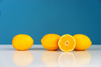 黄色的成熟的柠檬切片一半多汁的柑橘类水果的白色表格前面的<strong>蓝色</strong>的<strong>背景墙</strong>新鲜的水果