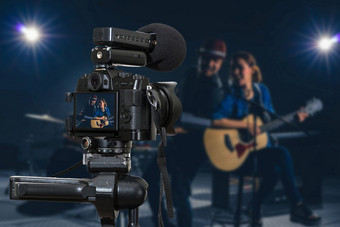 专业数字mirrorless相机与麦克风记录视频博客音乐家二人组乐队<strong>唱歌</strong>首歌和玩音乐仪器相机为摄影师视频和生活流媒体概念