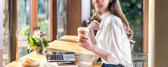 横幅肖像年轻的亚洲女人持有和喝杯咖啡和工作与技术移动PC咖啡商店自由职业者和企业家工作连接互联网通过电脑