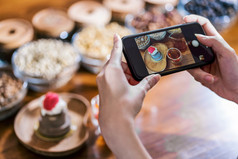 特写镜头移动电话采取照片蛋糕面包店与蜂蜜服务与咖啡壶的木表格咖啡馆商店和餐厅甜蜜的甜点和咖啡时间为社会网络概念