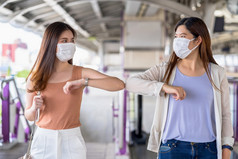 年轻的亚洲女人乘客穿外科手术面具和肘部撞与朋友在一起地铁火车当旅行大城市科维德爆发感染和流感大流行新正常的概念
