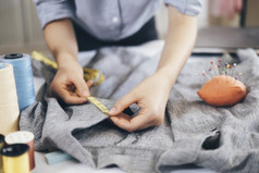 特写镜头年轻的女人裁缝采取测量夹克工作表格