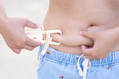 女孩显示持有和推的皮肤的肚子脂肪团与个人身体脂肪测试人员