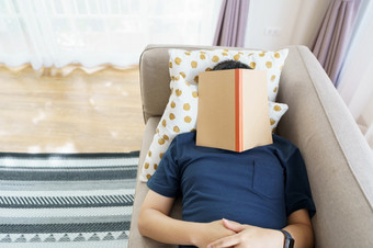亚洲英俊的男人。读书而睡觉男人。书封面睡意原因睡眠的概念足够的睡眠好睡眠