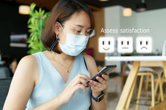亚洲女孩玩智能手机为选择给评级与快乐图标客户服务评价概念业务满意度调查