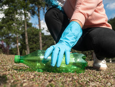 关闭手志愿者手套选择塑料瓶从的草的公园概念保存环境和停止塑料污染
