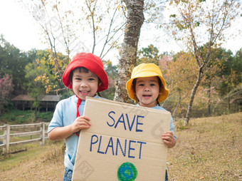 两个小孩子女孩兄弟姐妹持有保存的地球海报显示标志抗议对塑料污染的森林的概念世界环境一天零浪费