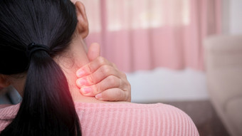 关闭女按摩她的痛苦的脖子引起的长时间的工作的电脑电话脖子梯形和肩膀疼痛肌肉痉挛