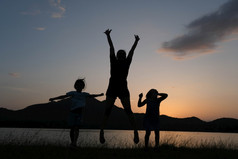 轮廓小女儿和妈妈。跳的湖日落快乐家庭玩在一起的花园健康的夏天活动为孩子们有趣的时间与家庭
