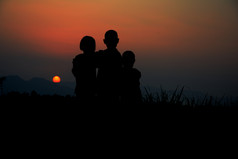 黑色的轮廓三个孩子们站在一起在那里天空日落