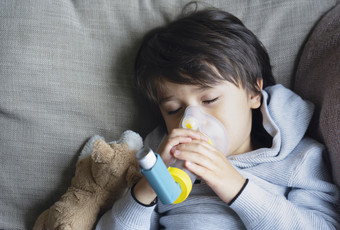 可怜的男孩累了从胸部咳嗽持有吸入器面具孩子下降睡眠而使用的volumtic为呼吸治疗试着孩子有哮喘过敏使用的哮喘吸入器