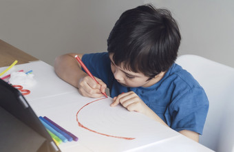 孩子红色的笔着色彩虹纸孩子使用数字平板电脑为家庭作业在线教训男孩享受艺术活动首页self-isolation在线教育首页学校教育距离学习概念