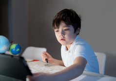 学校孩子使用平板电脑为他的家庭作业孩子男孩做家庭作业使用数字平板电脑搜索信息互联网后回来从学校电子学习首页学校教育教育概念