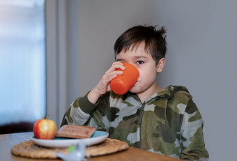 健康的孩子男孩喝橙色汁读<strong>苹果</strong>和巧克力烤面包机糕点孩子吃自制的早餐<strong>首页</strong>之前学校