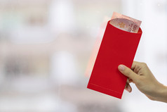 手持有红色的信封这它中国人月球新一年庆祝活动概念