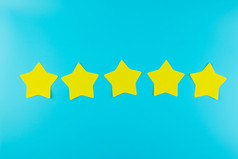五个明星黄色的纸请注意蓝色的背景与复制空间为文本客户评论反馈评级排名和服务概念
