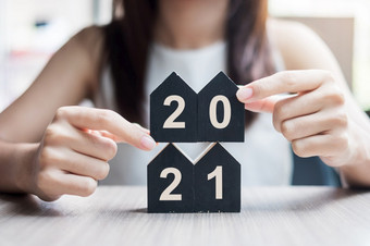 年轻的女商人手持有快乐新一年与房子模型表格办公室新房子金融财产保险真正的房地产储蓄和新一年决议概念