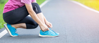 年轻的成人女运动服装系鞋带的公园户外运动员跑步者女人准备好了为运行和慢跑早....锻炼健康健康的生活方式和锻炼概念