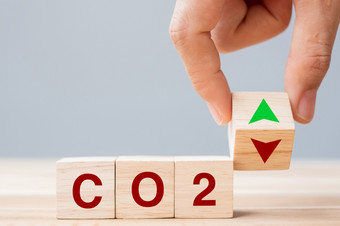 手翻转木多维数据集块和下来箭头象征与碳二氧化物文本表格背景免费的碳替代能源和全球气候改变概念