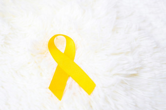 黄色的丝带白色背景为支持人生活和疾病9月自杀预防一天童年癌症意识月和世界癌症一天概念