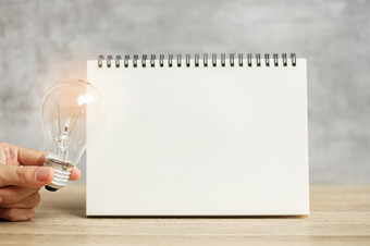 手持有灯泡在空白笔记本表格新的想法有创意的创新想象力灵感决议策略和目标概念