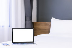 移动PC电脑与空白屏幕与聪明的电话白色床上装饰酒店卧室室内背景工作和业务休闲与旅行的假期概念