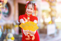 可爱的小亚洲女孩穿红色的传统的中国人旗袍装饰焦点显示持有黄色的信封手为中国人新一年节日中国人神社