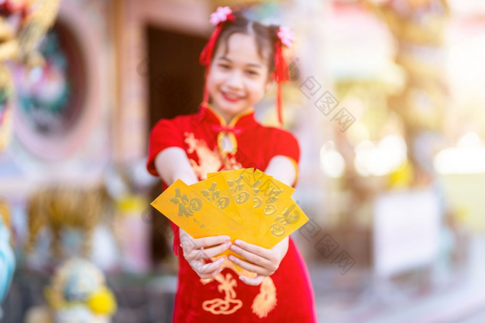 可爱的小亚洲女孩穿红色的传统的中国人旗袍装饰焦点显示持有黄色的信封手为中国人新一年节日中国人神社