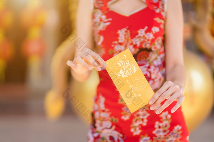 特写镜头女人穿红色的传统的中国人旗袍装饰持有黄色的信封手为中国人新一年节日中国人神社泰国