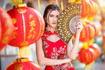 肖像美丽的微笑亚洲年轻的女人穿红色的传统的中国人旗袍装饰和持有与纸灯笼中国人范宁为中国人新一年节日中国人神社