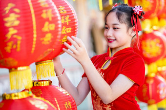 肖像美丽的微笑小可爱的亚洲女孩穿红色的传统的中国人旗袍红色的纸灯笼装饰为中国人新一年节日中国人神社