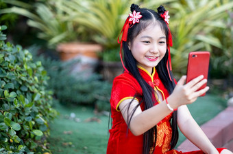 肖像美丽的微笑可爱的小亚洲女孩穿红色的传统的<strong>中国</strong>人旗袍装饰采取自拍与智能手机为<strong>中国</strong>人新一年节日<strong>中国</strong>人神社