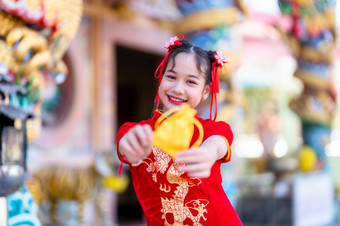 肖像美丽的微笑可爱的小亚洲女孩穿红色的传统的中国人旗袍装饰焦点显示金钱袋为中国人新一年节日中国人神社泰国