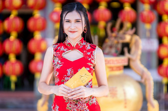 肖像亚洲年轻的女人穿红色的传统的<strong>中国</strong>人旗袍装饰持有黄色的信封与的<strong>中国</strong>人文本祝福写好运气为<strong>中国</strong>人新一年节日