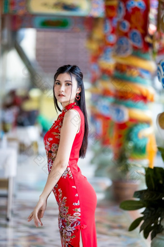 肖像美丽的微笑亚洲年轻的女人穿红色的传统的中国人旗袍装饰为中国人新一年节日中国人神社泰国