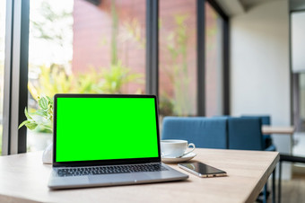 模型移动PC电脑与空屏幕与咖啡杯和智能手机<strong>表格</strong>的咖啡商店背景绿色屏幕
