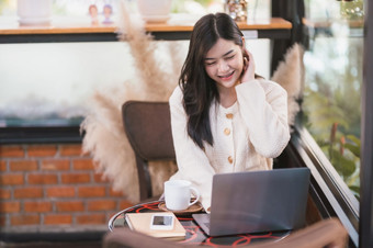 肖像自由业务美丽的积极的微笑年轻的亚洲女人女孩穿温暖的衣服在线工作与移动PC电脑与咖啡杯<strong>杯子</strong>房子<strong>首页</strong>的生活房间内部咖啡馆